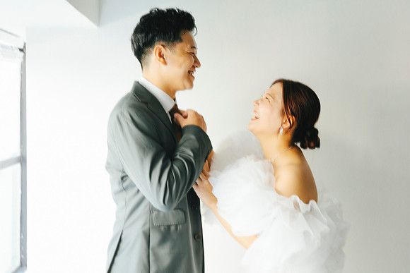 Bride and groom laughing together indoors during their wedding photography session.